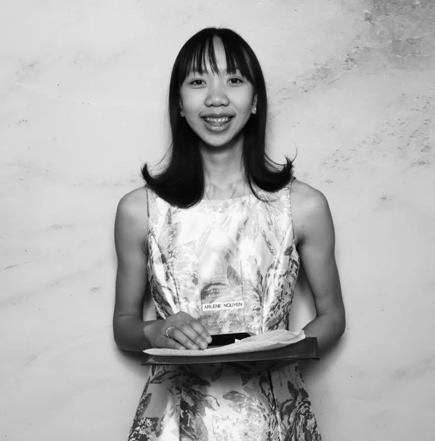 this is a black and white photobooth photo of NHCC student, Arlene smiling and holding up her Student Life Award certificate.