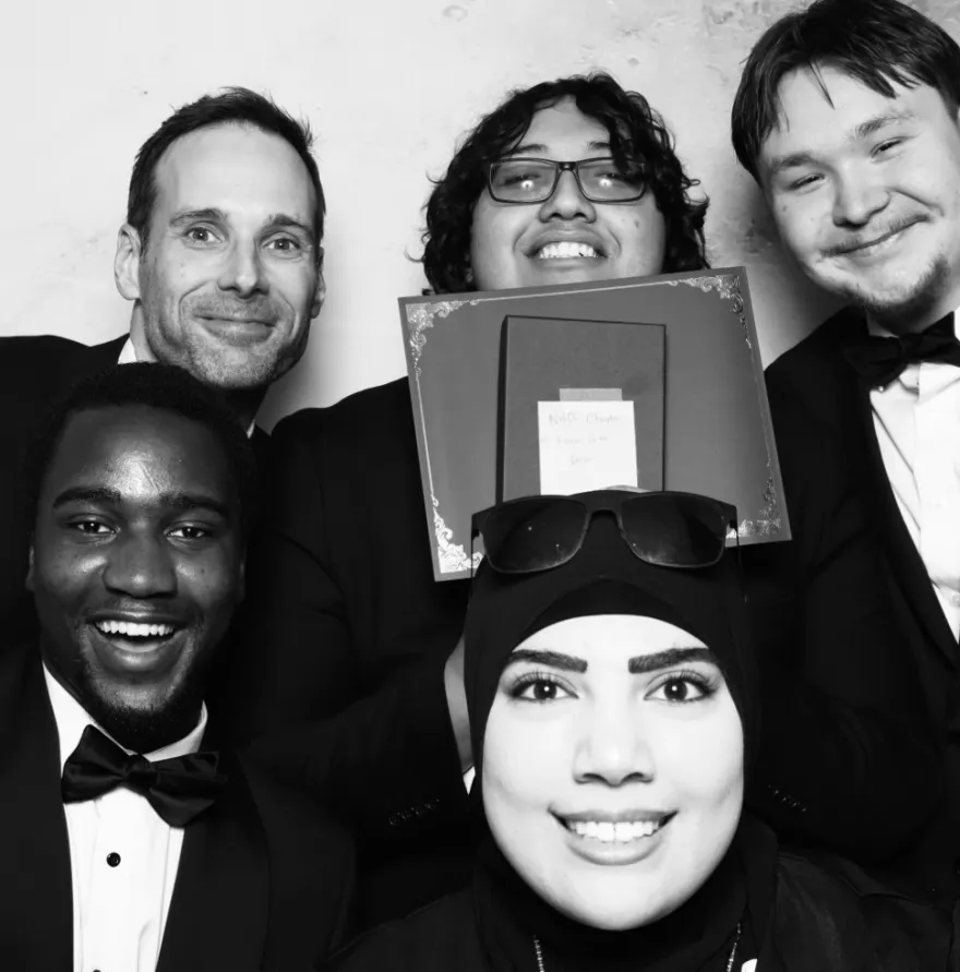 this is a black and white photobooth photo of a faculty advisor and four NHCC student members of our KBD honors society, smiling for the camera. 