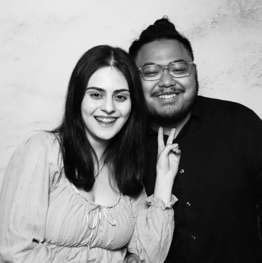 this is a black and white photobooth photo of NHCC student, Kendall smiling next to NHCC graduate, Asal.