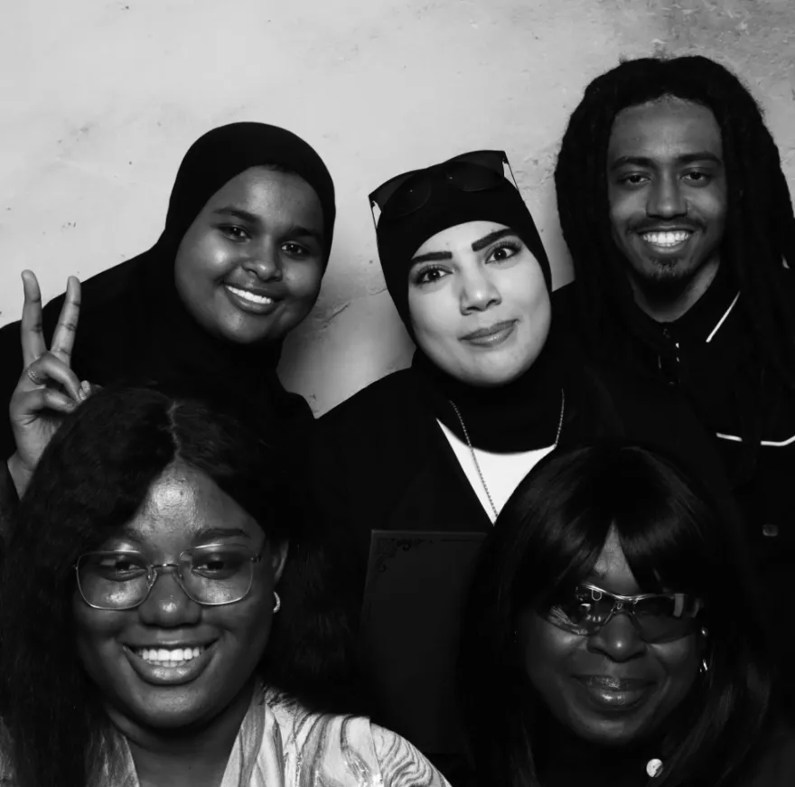 this is a black and white photobooth photo of five NHCC students smiling for the camera. 