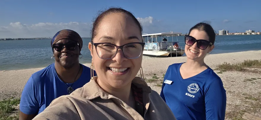 this is a group photo of business professor, Belinda Armstead by the beach, smiling with two other people at an educational conference in Florida.