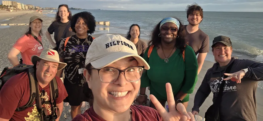 this is a group photo of business professor, Belinda Armstead by the beach, smiling with a big group of other people at an educational conference in Florida.