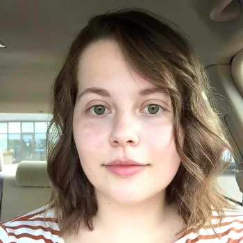 graphic design student Ingrid Helgerson sitting inside her car smiling for the camera