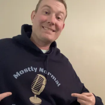 student AJ Eide posing and pointing to the design on his hoodie reading, Mostly normal gamers podcast