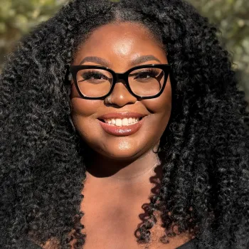 woman wearing glasses smiling outside