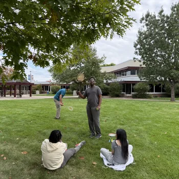 man standing in the center outside holding badminton equipment
